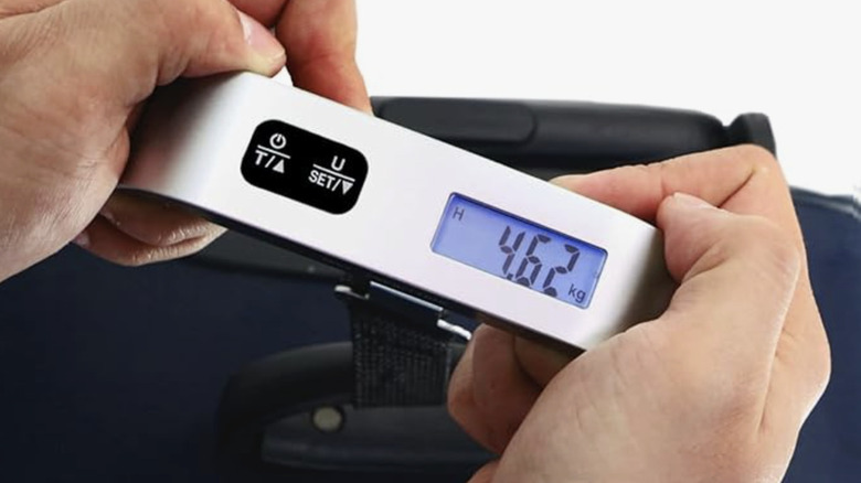 Mains tenant une balance à bagages