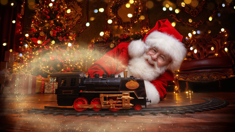 Père Noël souriant et jouant avec un train à vapeur miniature