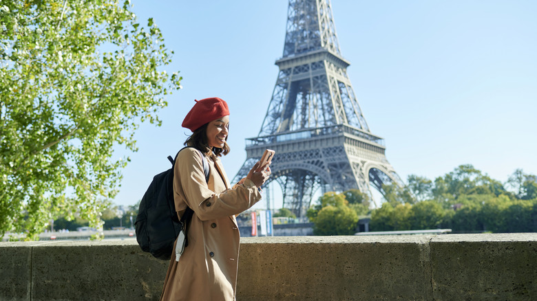 femme regardant un téléphone portable, la Tour Eiffel, des arbres