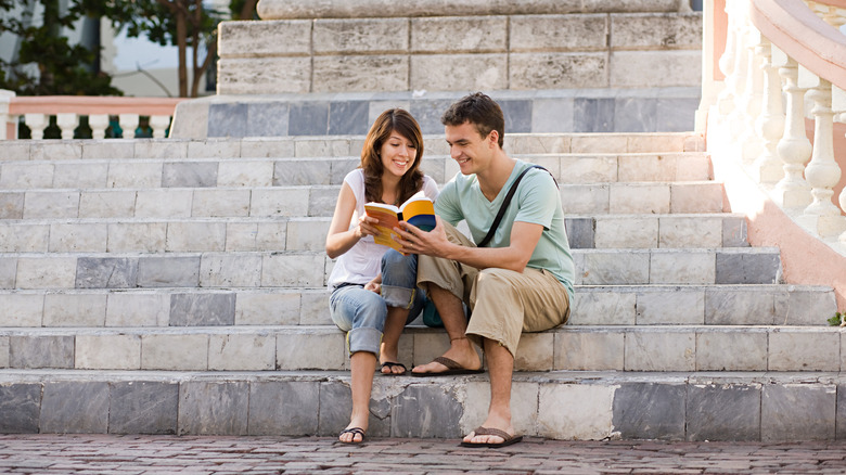 couple assis sur les marches avec un livre
