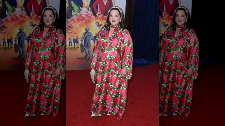 Melissa McCarthy souriante en portant une robe à imprimé roses