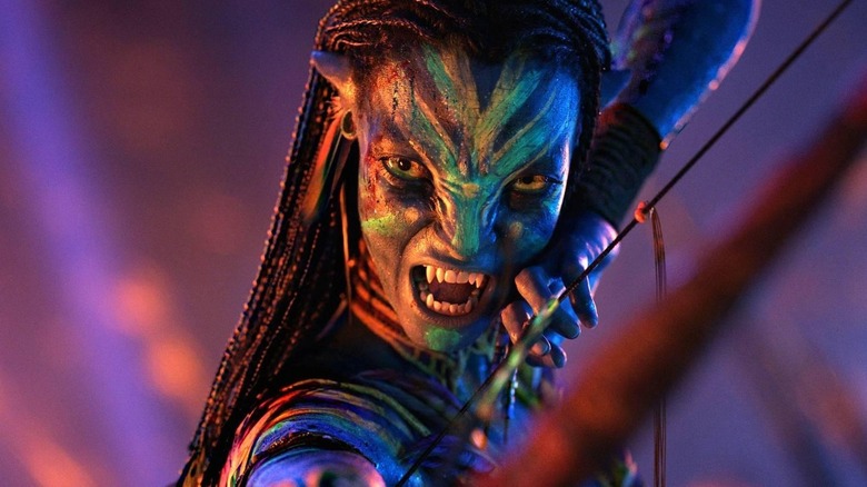 Zoe Saldaña dans le rôle de Neytiri avec son arc et ses flèches armés dans Avatar : Fire and Ash