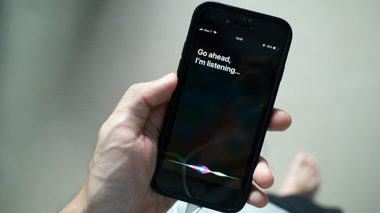Une personne tenant un vieil iPhone présentant Siri.