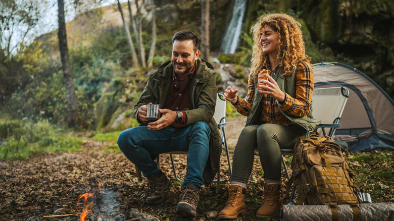 Un couple mangeant et parlant près d’un feu de camp