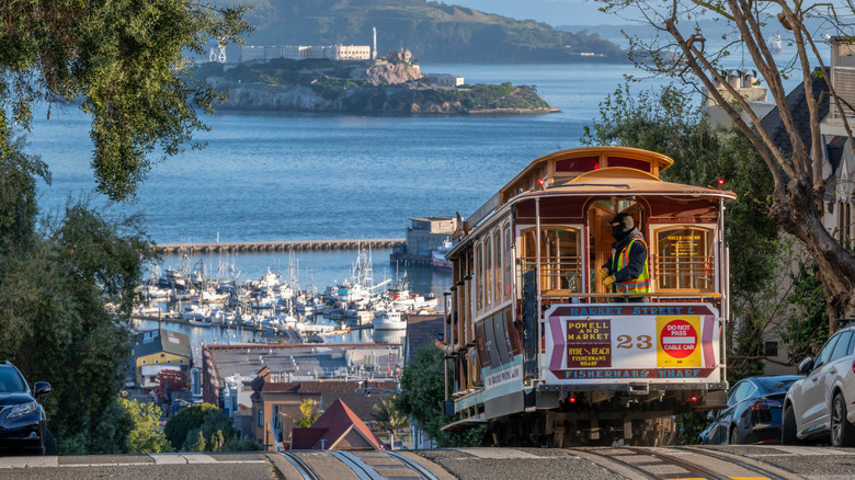 Téléphériques de San Francisco qui montent une colline avec Alcatraz en arrière-plan