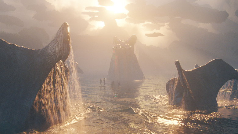 Plusieurs Tulkun ressemblant à des baleines franchissant l'eau et entourant quelques minuscules personnages dans Avatar : Fire & Ash