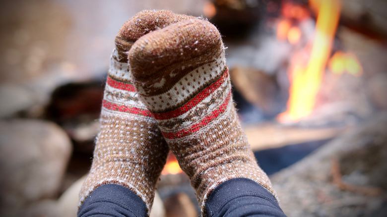 pieds avec des chaussettes mérinos près d'un feu de camp