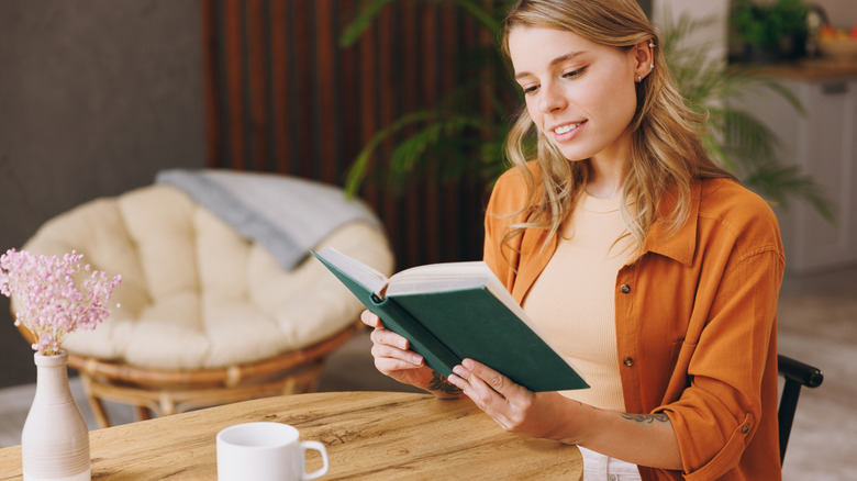 jeune femme heureuse lisant un roman au café