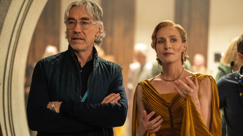 Le showrunner Tony Gilroy debout, les bras croisés à côté de Geneviève O'Reilly dans le rôle de Mon Mothma sur le tournage de la saison 2 d'Andor