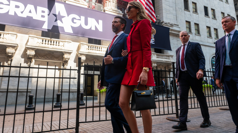 Bettina Anderson en tailleur jupe rouge avec Donald Trump Jr marchant dehors