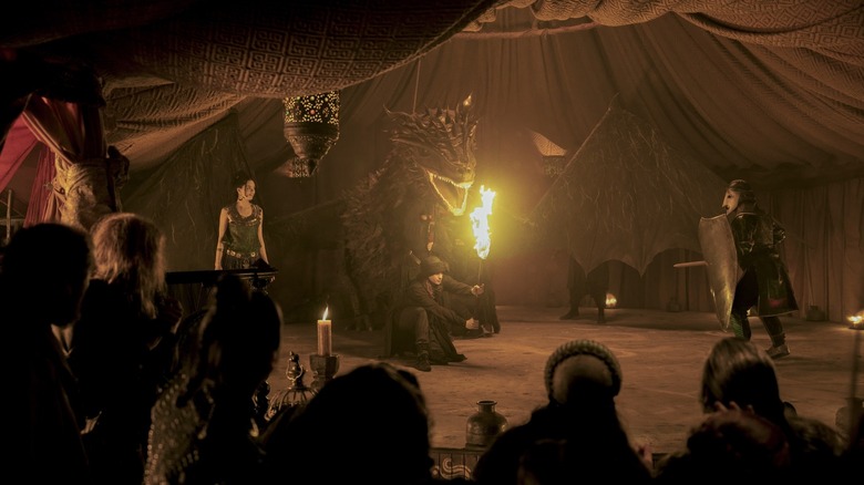 Tanzyn Crawford dans le rôle de Tanselle présente un spectacle de marionnettes élaboré avec une maquette d'un dragon cracheur de feu dans Un Chevalier des Sept Royaumes