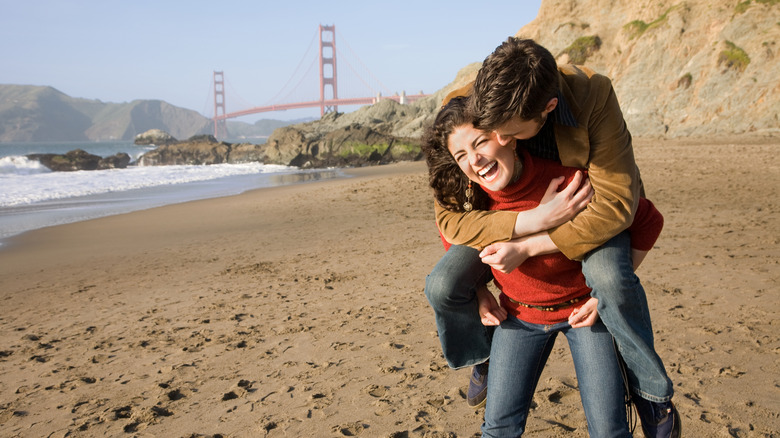 Un couple sur la plage avec le Golden Gate Bridge en arrière-plan