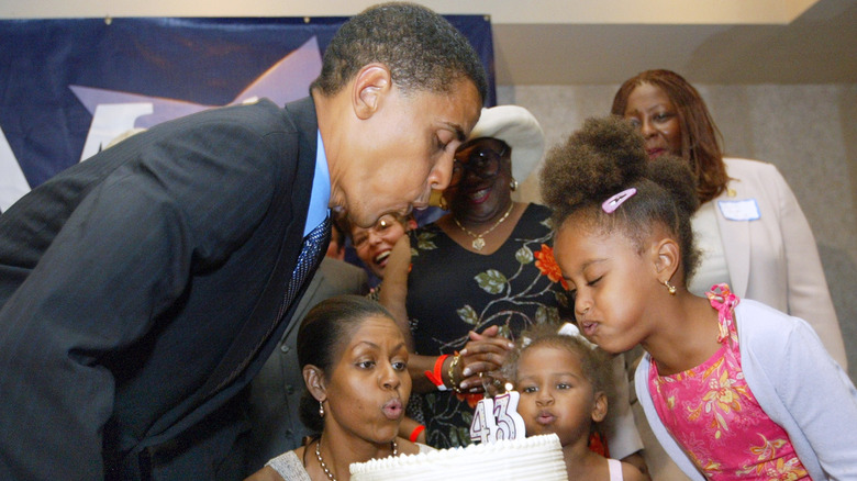 La jeune Malia Obama, coiffée en plusieurs poufs, soufflait les bougies d'un anniversaire avec sa famille en 2004.