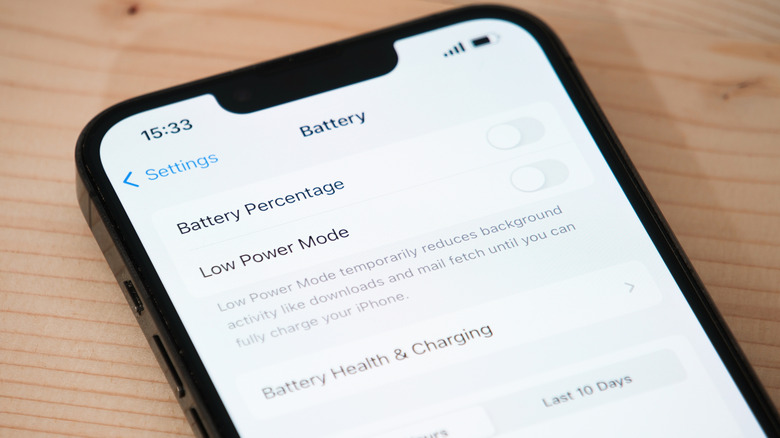 iPhone sur une surface en bois avec écran de gestion de la batterie ouvert