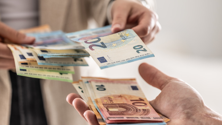 Mains échangeant des billets en euros
