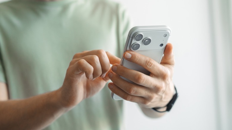 Personne portant un t-shirt vert avec un iPhone 17 Pro