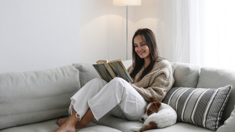 Une femme lit sur le canapé avec son chien