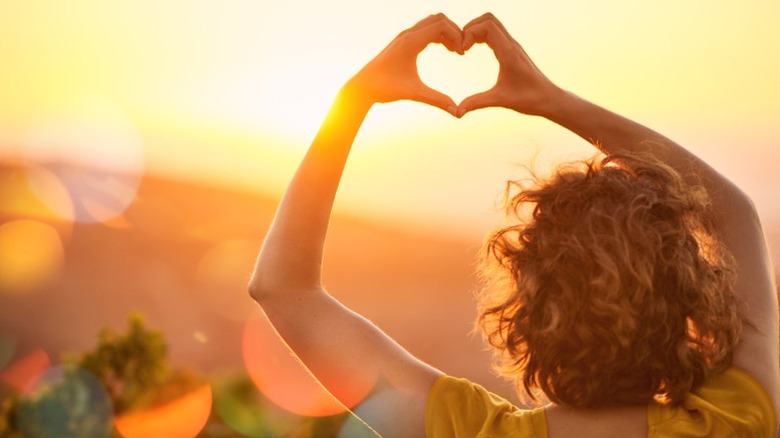 Une femme lève les mains en forme de coeur