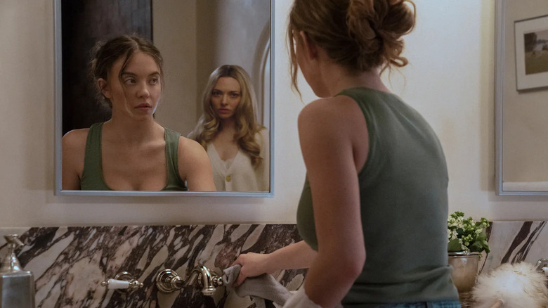 Millie fait le ménage avec Nina derrière elle dans le miroir dans The Housemaid