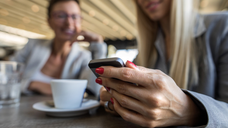 Personne utilisant un smartphone dans un café.