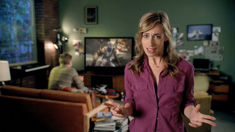 Une mère debout devant son fils alors qu'il joue à God of War à la télévision dans une publicité pour PlayStation 3.