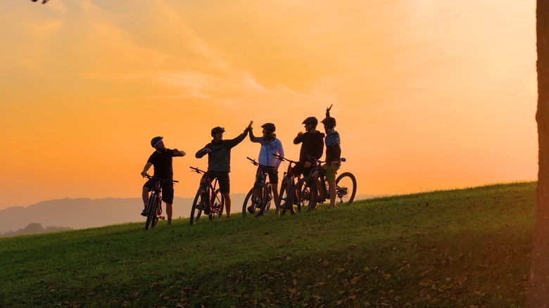 Un groupe de cinq hommes en VTT sur le flanc d’une colline au crépuscule