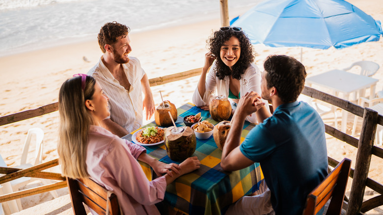 Un groupe de quatre amis dînant dans un restaurant en bord de mer