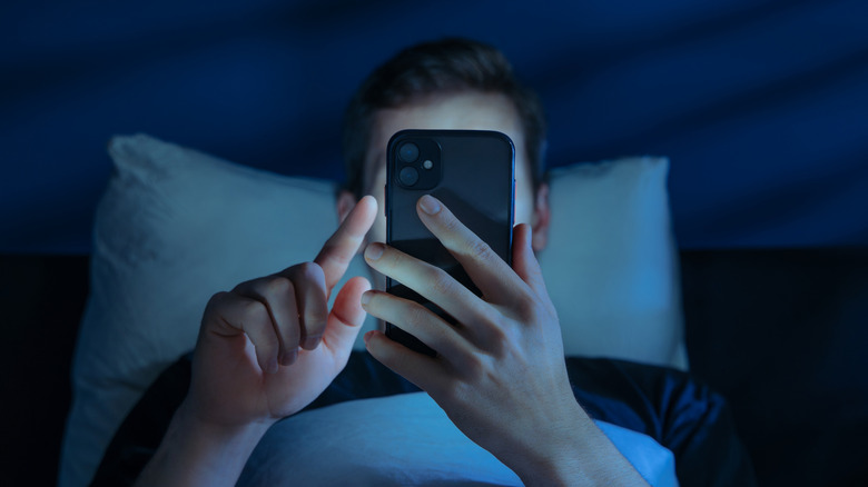 homme au lit la nuit sur son smartphone