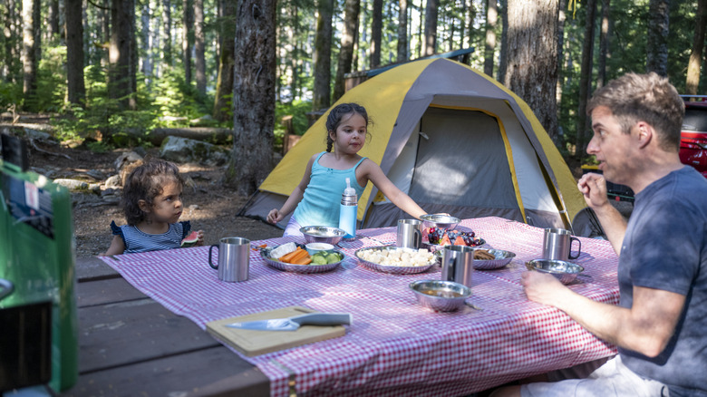 Famille mangeant à une table de pique-nique au camping en forêt
