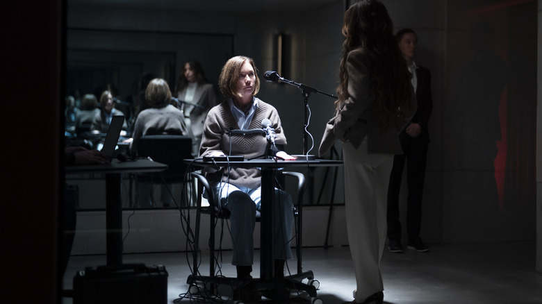 Julianne Nicholson dans le rôle de Sinatra assise dans une salle d'interrogatoire avec Sarah Shahi dans le rôle de Gabriela Torabi debout devant elle et Nicole Brydon Bloom dans le rôle de Jane Driscoll en arrière-plan dans Paradise saison 2