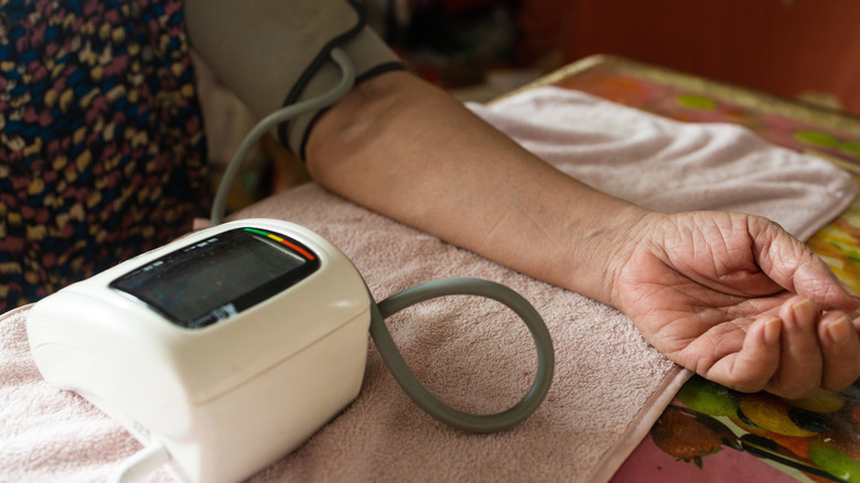 Gros plan du bras d'une personne posé sur une table avec un tensiomètre.