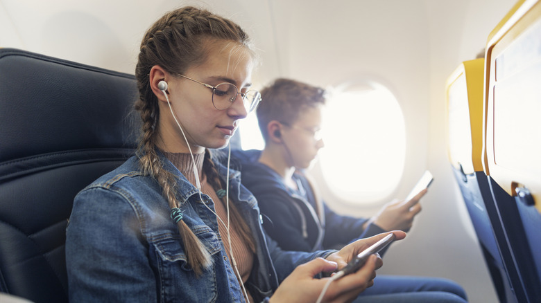 Des adolescents utilisent des écouteurs dans un avion.