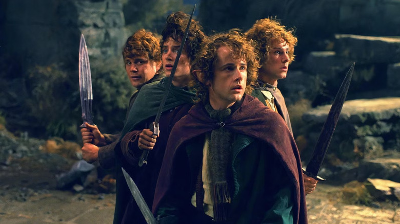 Sam, Frodon, Pippin et Merry au sommet d'une colline tenant des épées dans Le Seigneur des Anneaux : La Communauté de l'Anneau