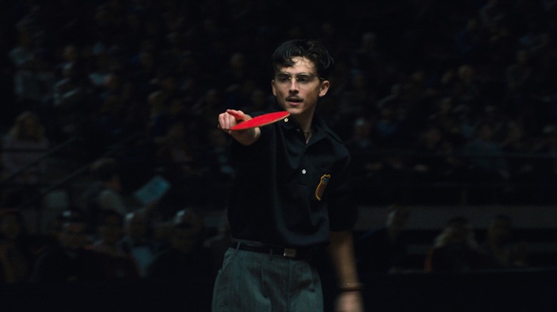 Un Timotheé Chalamet arrogant tient une raquette de tennis de table dans Marty Supreme