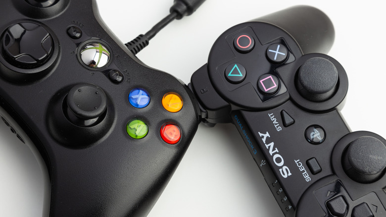 Un gros plan d'une manette PS3 et Xbox 360 sur une surface blanche.