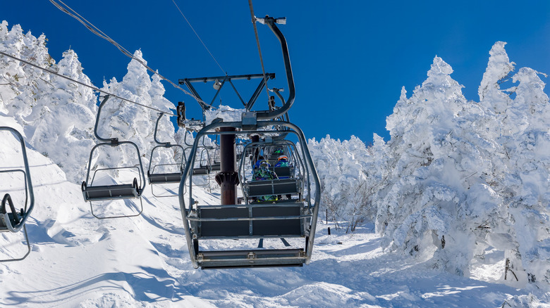 Vue à la première personne depuis un télésiège montant une montagne enneigée dans une station de ski au Japon.