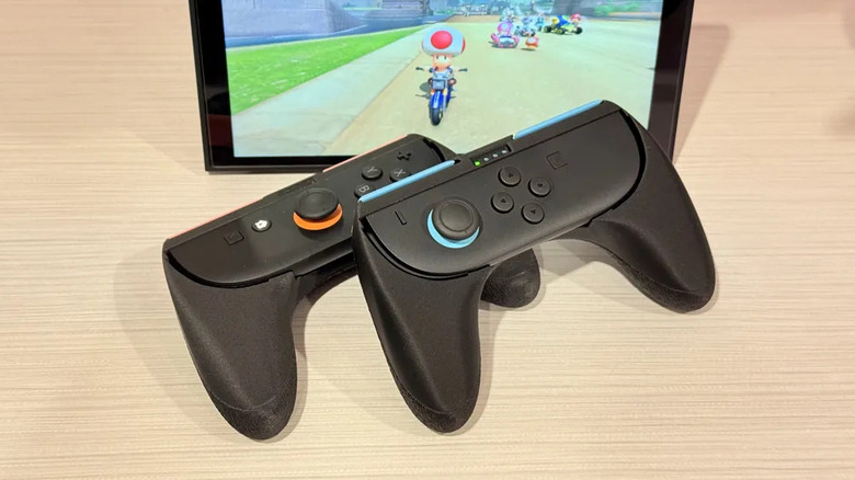 Deux Joy-Cons Nintendo Switch et la poignée de la manette ConJoy placés devant une unité Nintendo Switch