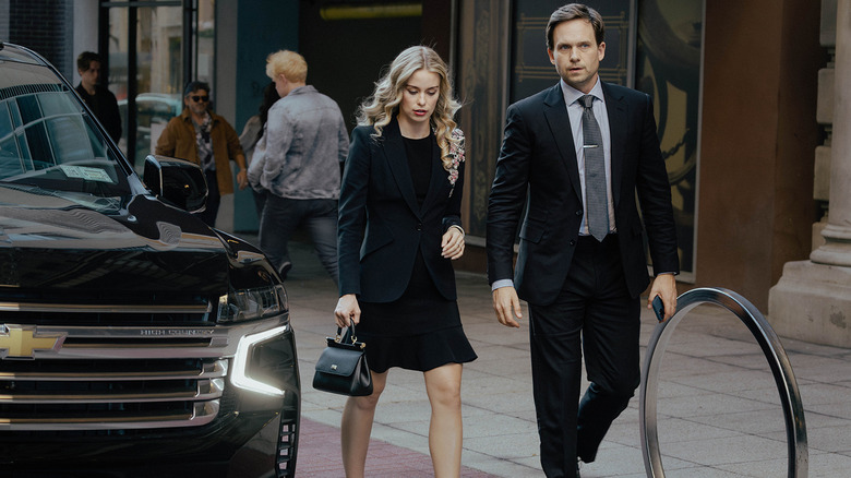 Paige McIntosh d'Elle Chapman marche le long d'un trottoir de New York à côté de Russell McIntosh de Patrick J. Adams dans The Madison