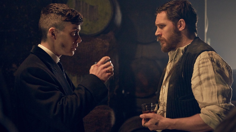 Cillian Murphy dans le rôle de Tommy Shelby prenant un verre avec Tom Hardy dans le rôle d'Alfie Solomons dans un entrepôt de Peaky Blinders