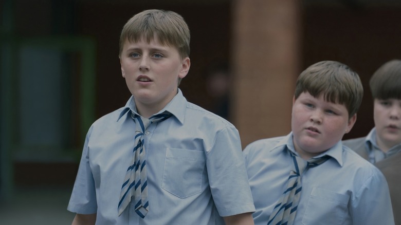 Dudley Dursley et ses amis regardent Harry dans Harry Potter à l'école des sorciers