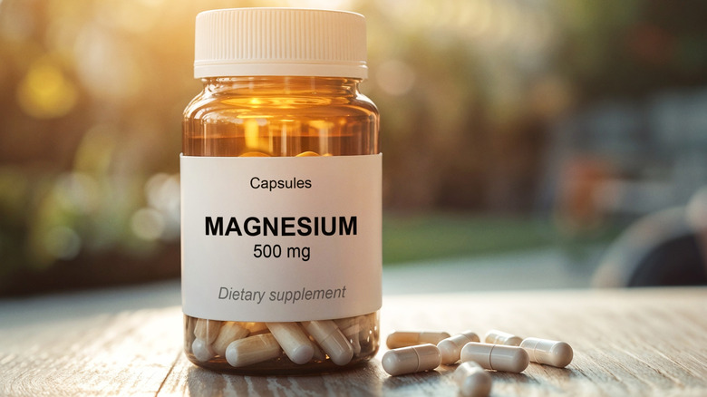 Bouteille de magnésium et capsules sur une table avec l'extérieur flou en arrière-plan