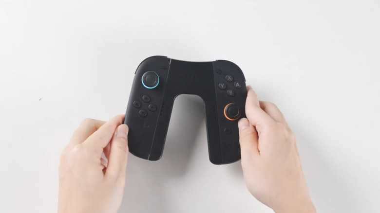 Une poignée Joy-Con de chargement Switch 2 tenue entre deux mains.