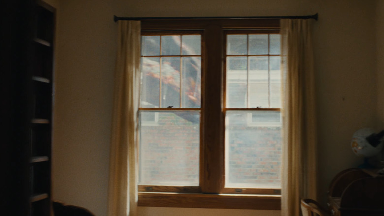 Un dinosaure marchant près de la fenêtre dans The End of Oak Street