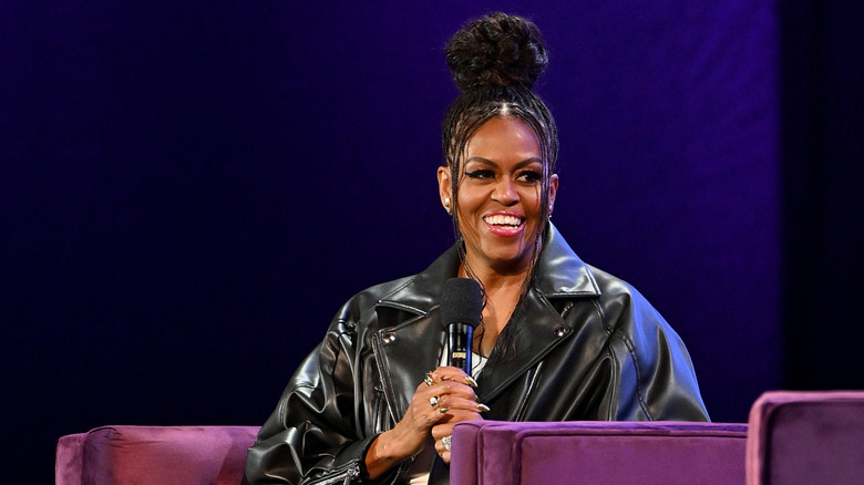 Michelle Obama tient un micro et porte une veste en cuir