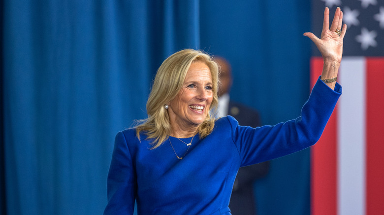 Jill Biden sourit et salue en portant une robe bleue