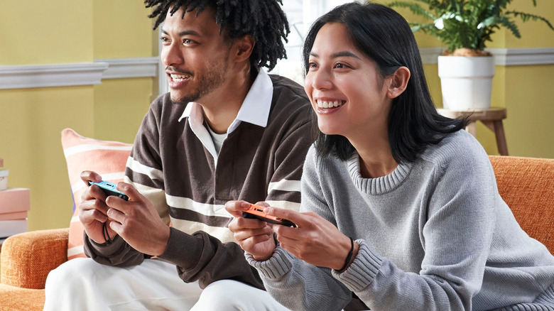 Deux personnes jouant à la Nintendo Switch 2 avec des Joy-Cons sur un canapé.