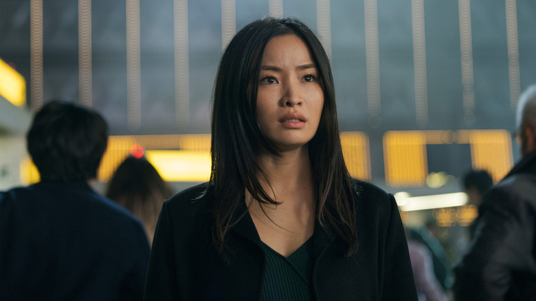 Anna Sawai dans le rôle de Cate Randa vêtue de noir et debout au milieu d'une foule dans Monarch : Legacy of Monsters