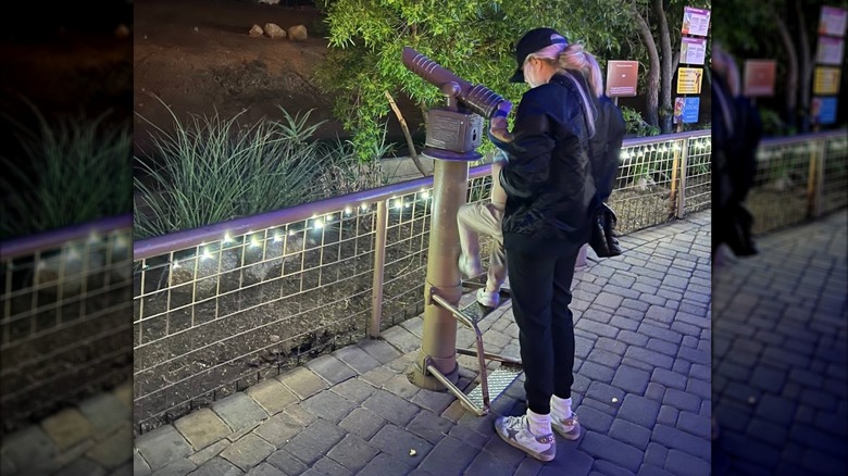 Erika Kirk dans un survêtement noir avec des baskets grises regardant hors du télescope