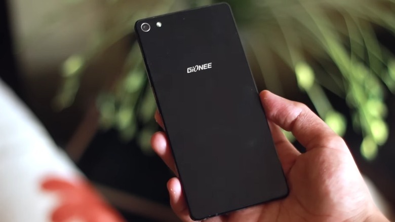 Main tenant un Gionee Elife S7 devant une plante floue