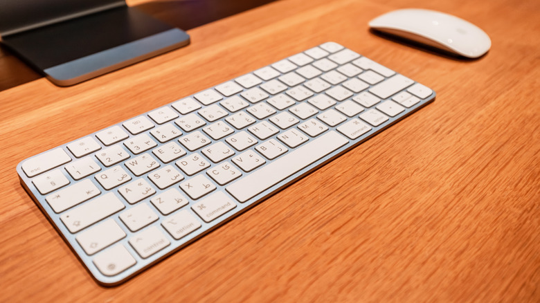 Clavier et souris magiques sur un bureau devant un ordinateur